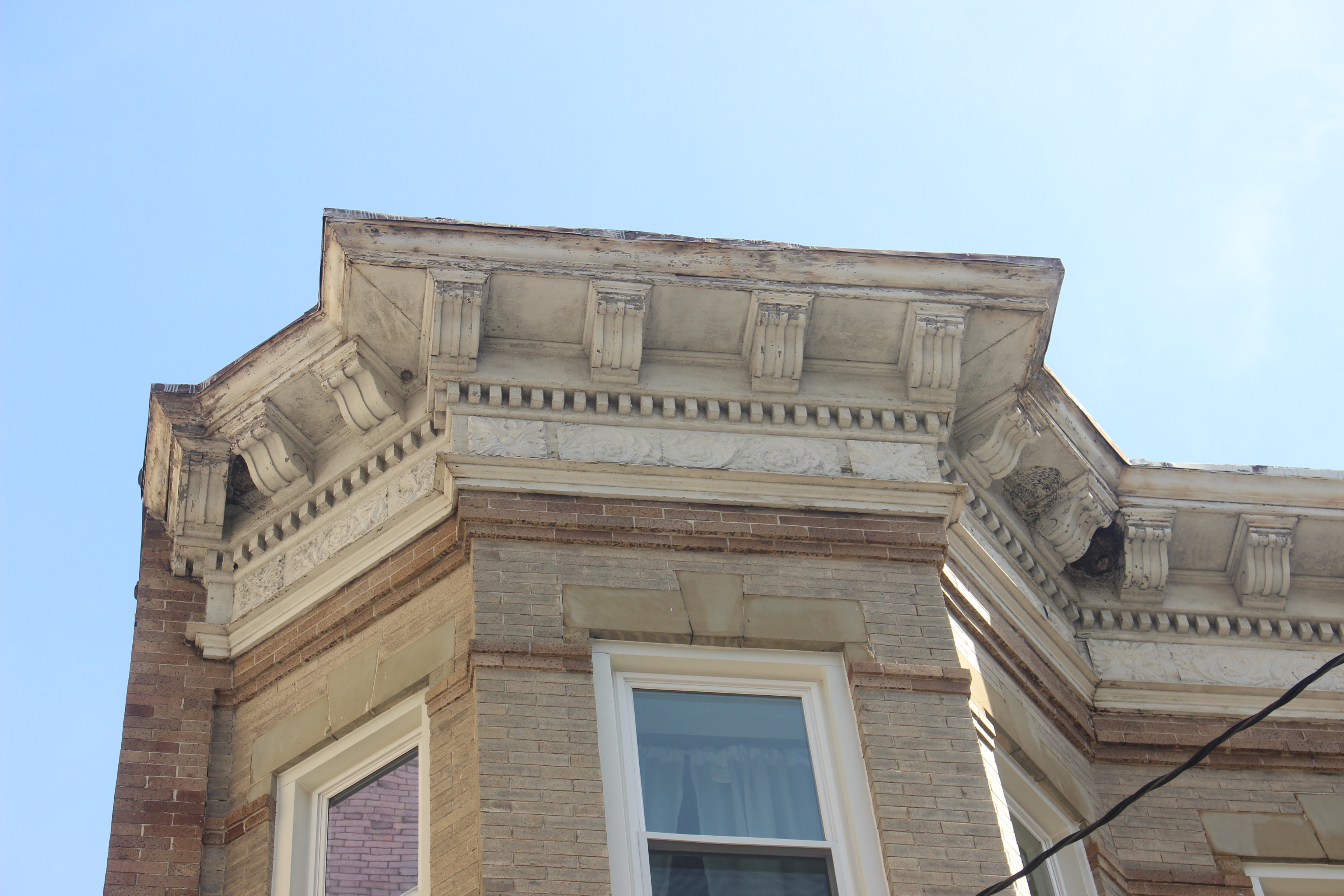 Image of four wasp nests under one roof ledge