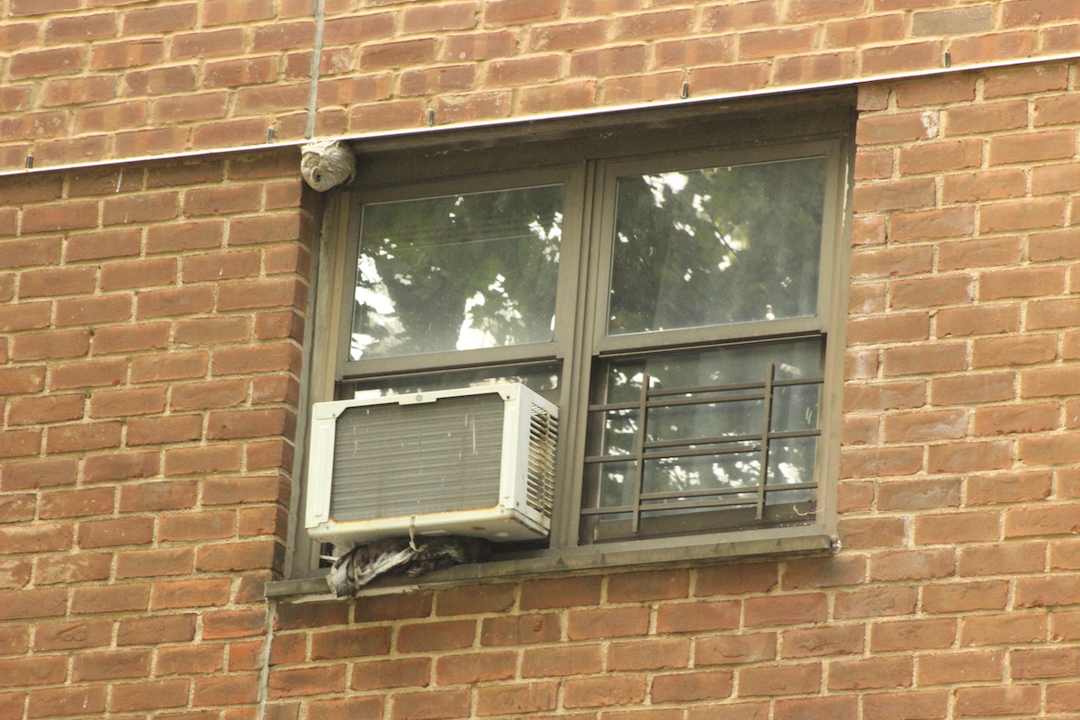 A wasp nest above someone's air conditioner.